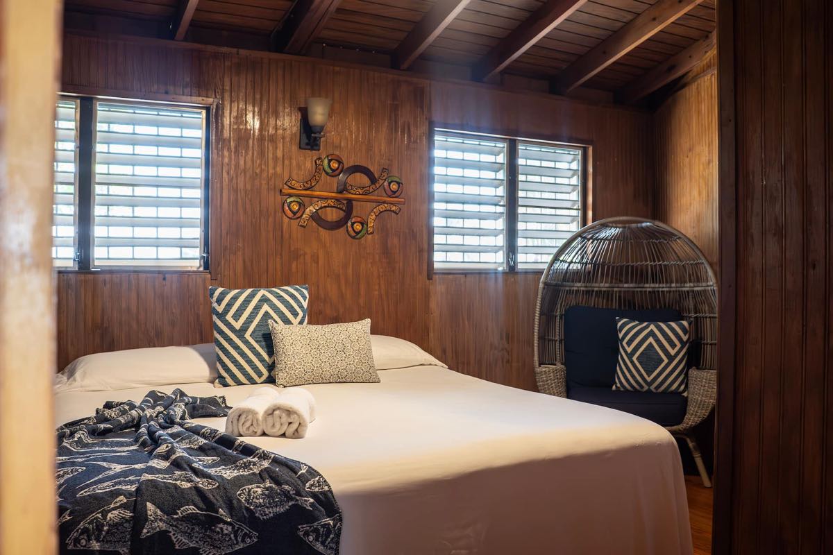 Habitación king con sábanas blancas y vista por la ventana